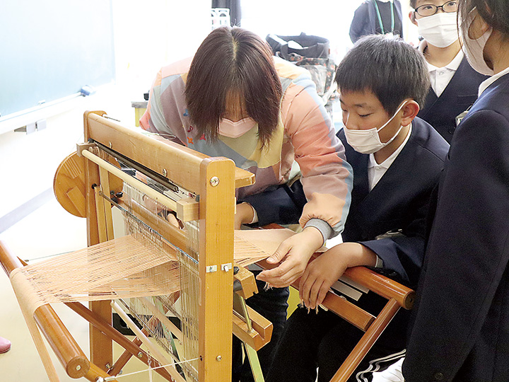指導を受けながら手織り機を体験する児童