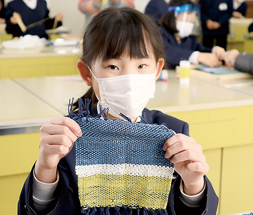 オリジナルの手織りのハンカチを手にする児童