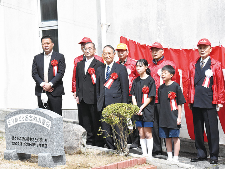 西志和小閉校の石碑と記念撮影する参加者たち （撮影・三好）