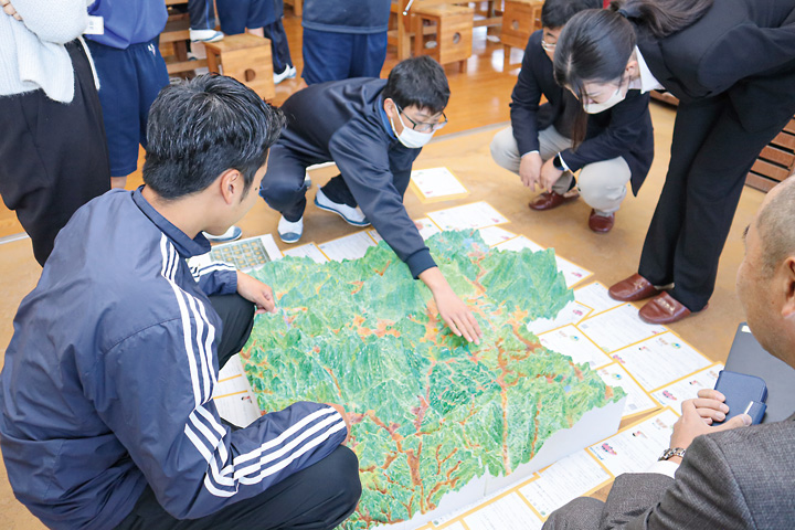 完成した豊栄町の立体地図上で、自分の家などを確認する生徒（撮影・山北）