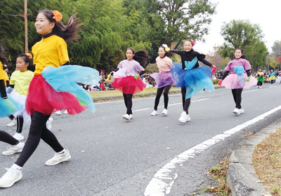 笑顔でダンスを披露しながらパレードする市民ら