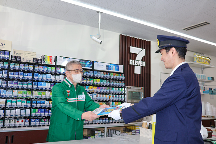 セブンイレブン西條西本町店のオーナー(左)に名前を記載したパトロールボードを手渡す担当警察官